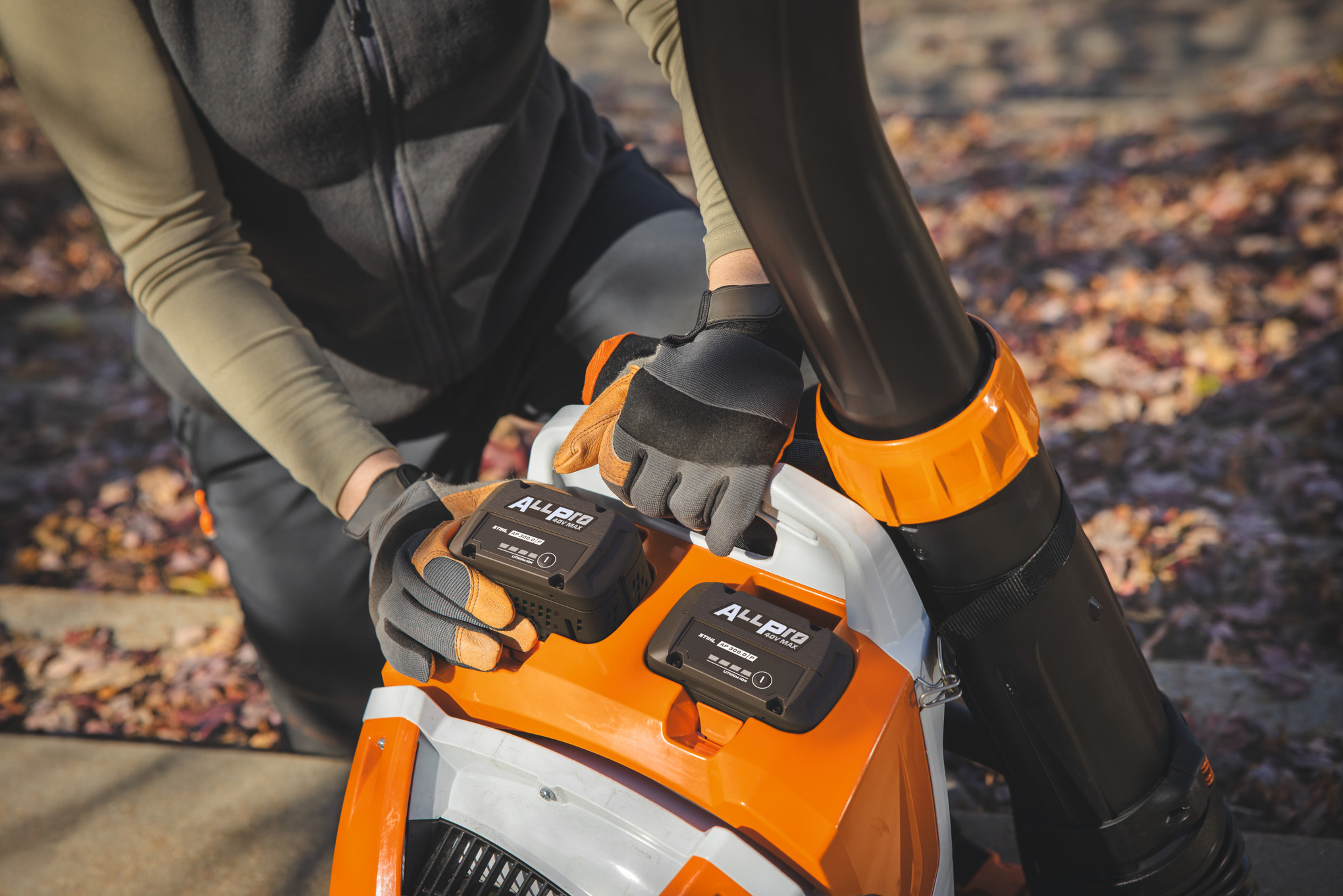 En profesjonell landskapspleier setter det andre STIHL-batteriet AP 300.0 P i STIHL-batteriryggeblåseren.