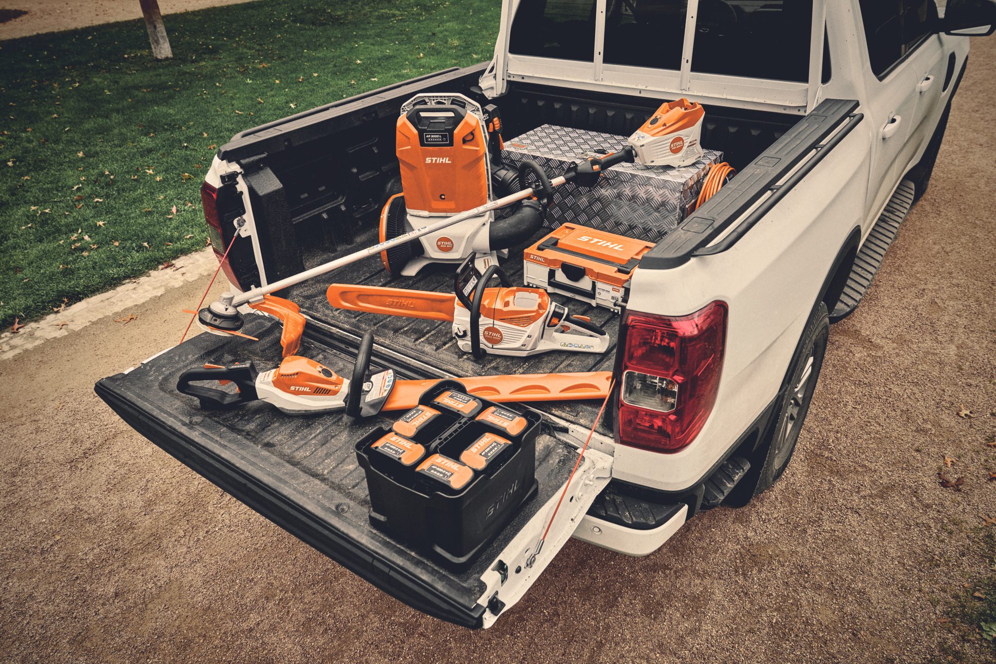 Forskjellige batteriverktøy og matchende batterier fra STIHL AP-systemet på lasteplanet til et kjøretøy  