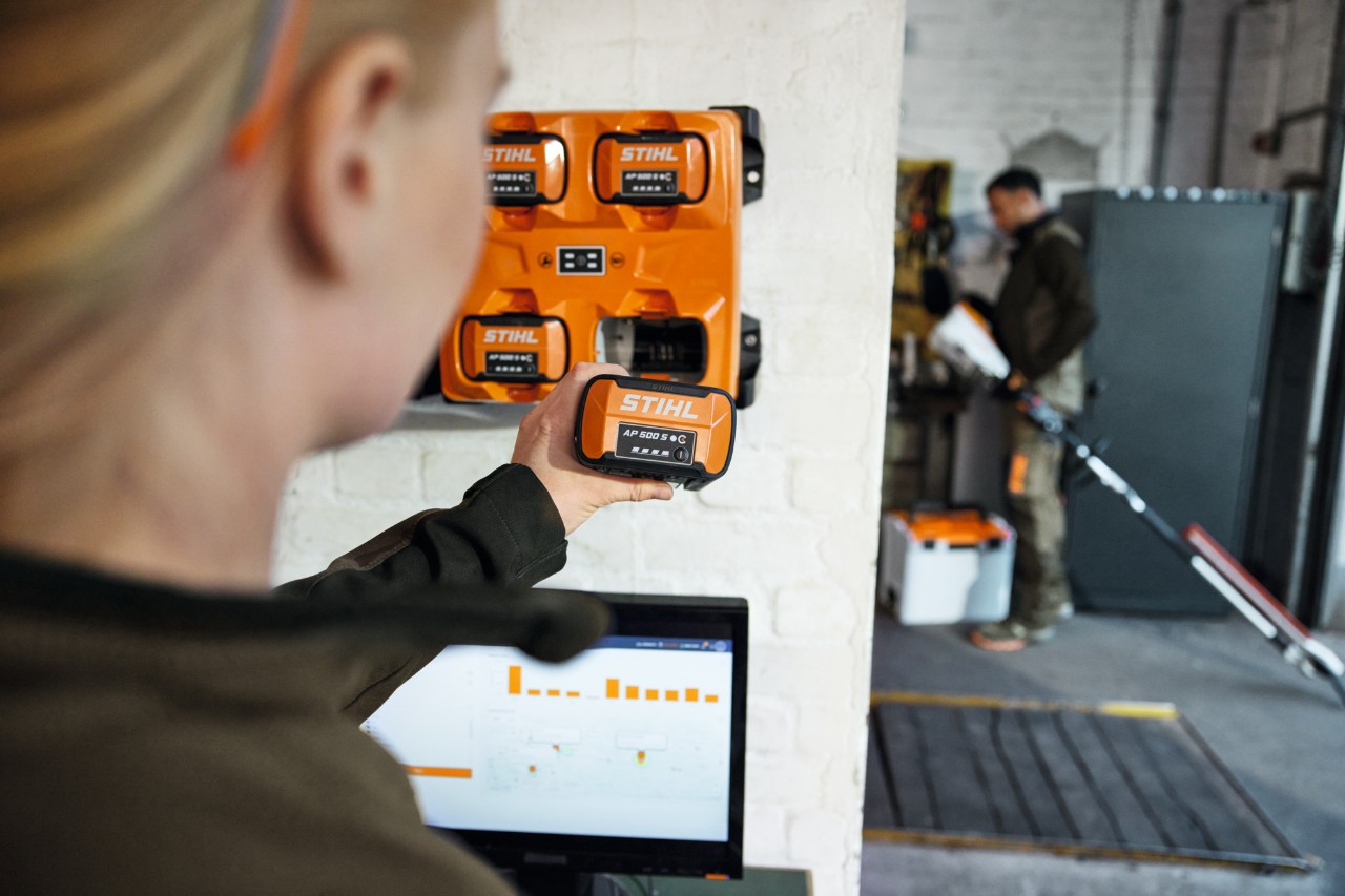 En kvinne foran en bærbar PC tar en AP 300 S ut av en STIHL AL 301-4 multilader