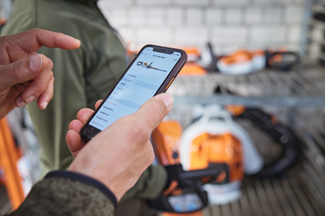 Personen på lageret sjekker datoen i STIHL connected-appen på smarttelefonen.