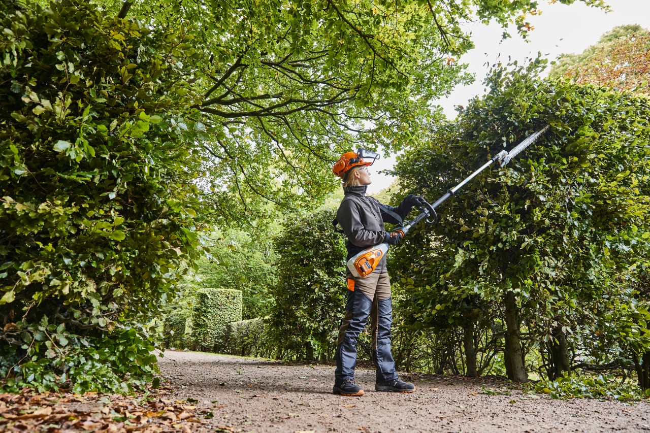 En anleggsgartner beskjærer en hekk med en STIHL HLA 135 batteridrevet hekksaks med lang rekkevidde.