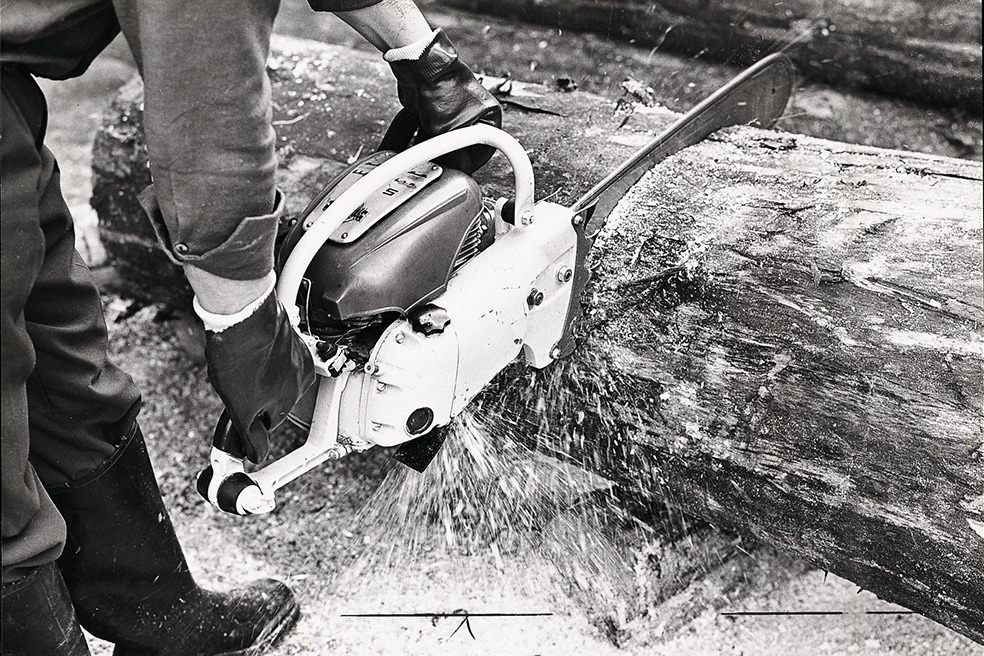 Gammelt svart-hvitt bilde av en person som kapper et tre med en STIHL Contra motorsag 