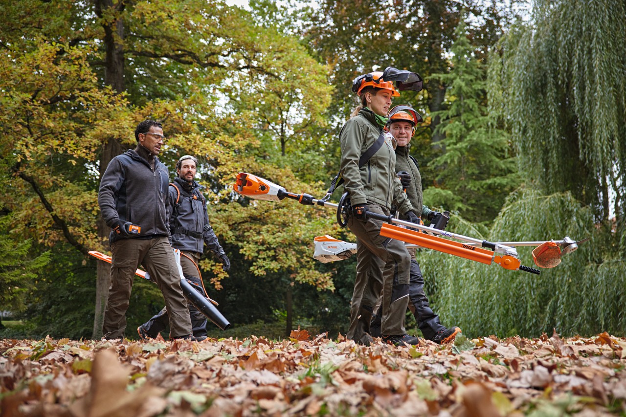 Fire fagfolk fra STIHL med batteridrevne verktøy går langs en sti