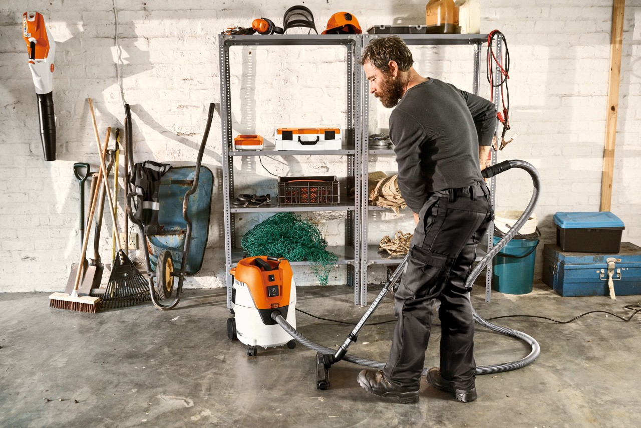 Mann som støvsuger gulvet i en garasje med en STIHL SE 62 E våt- og tørrstøvsuger