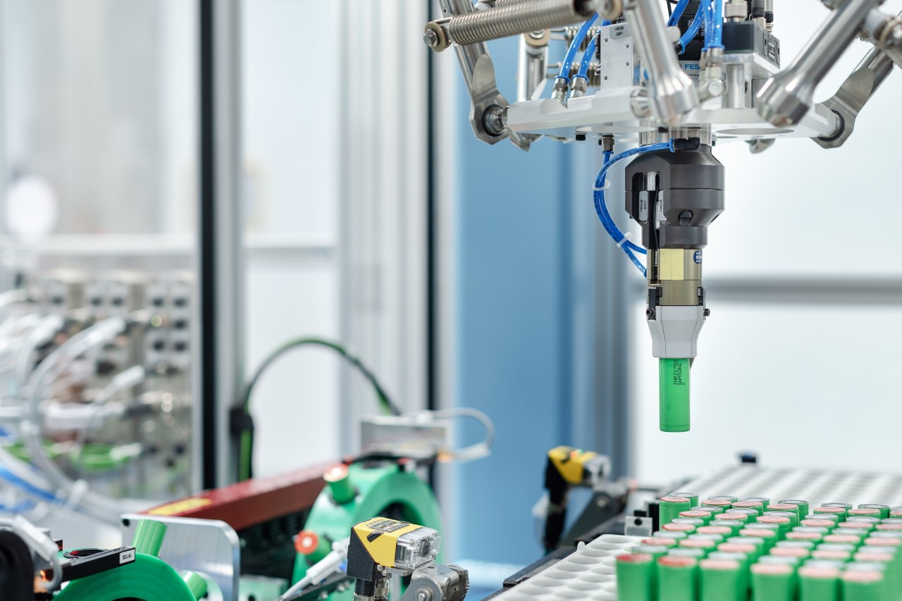 En robotarm utstyrer celleholderne med battericeller