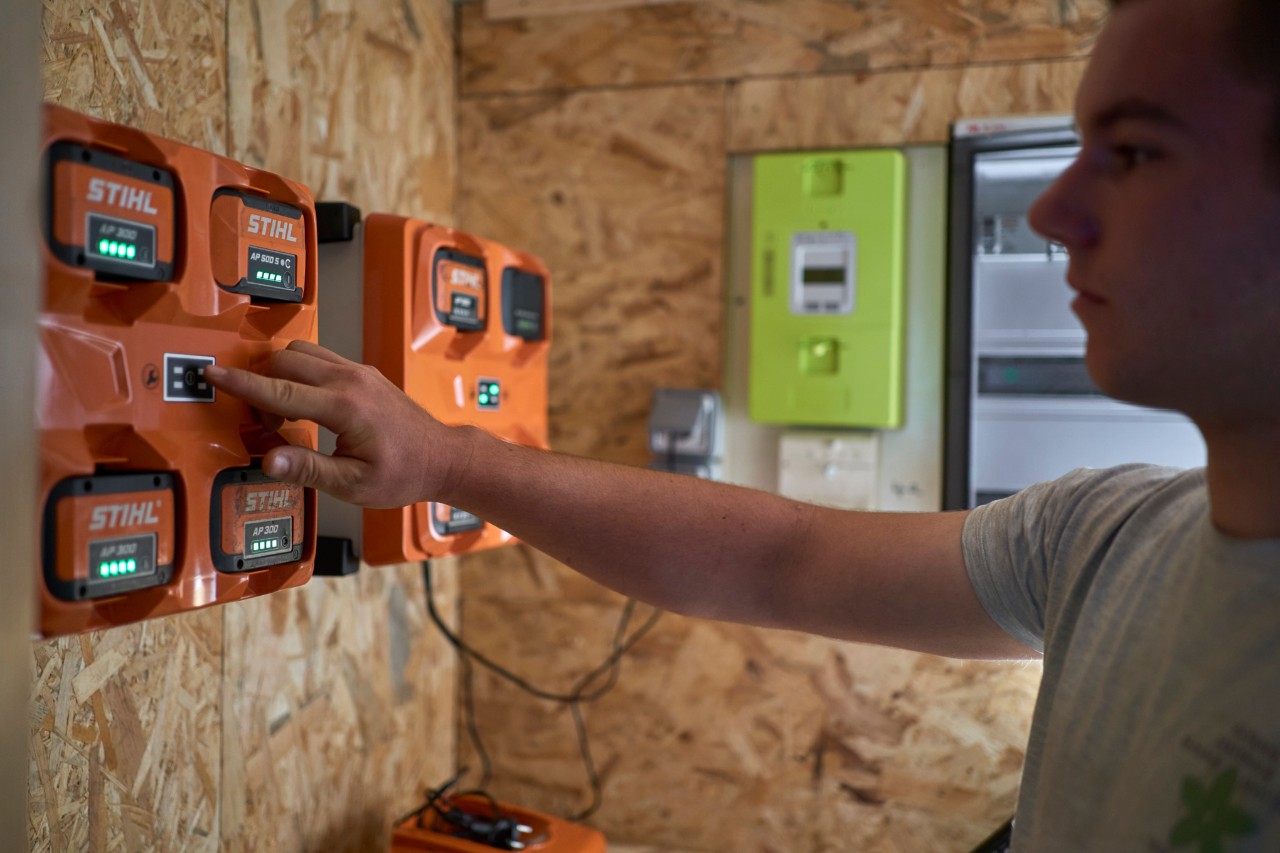 En mann står ved en batteriladestasjon