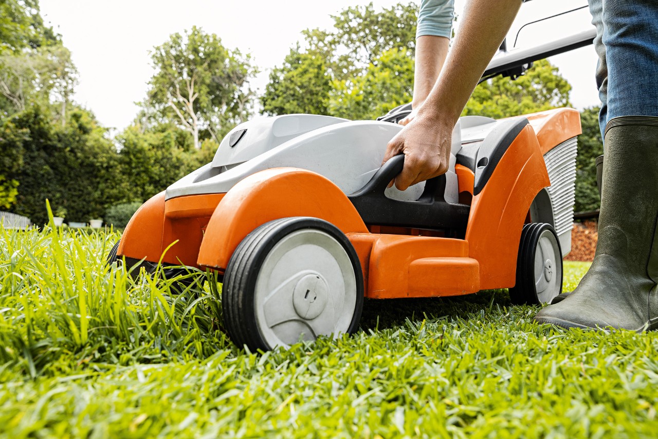  En kvinne stiller inn klippehøyden på en batteri-gressklipper RMA 339 C fra STIHL