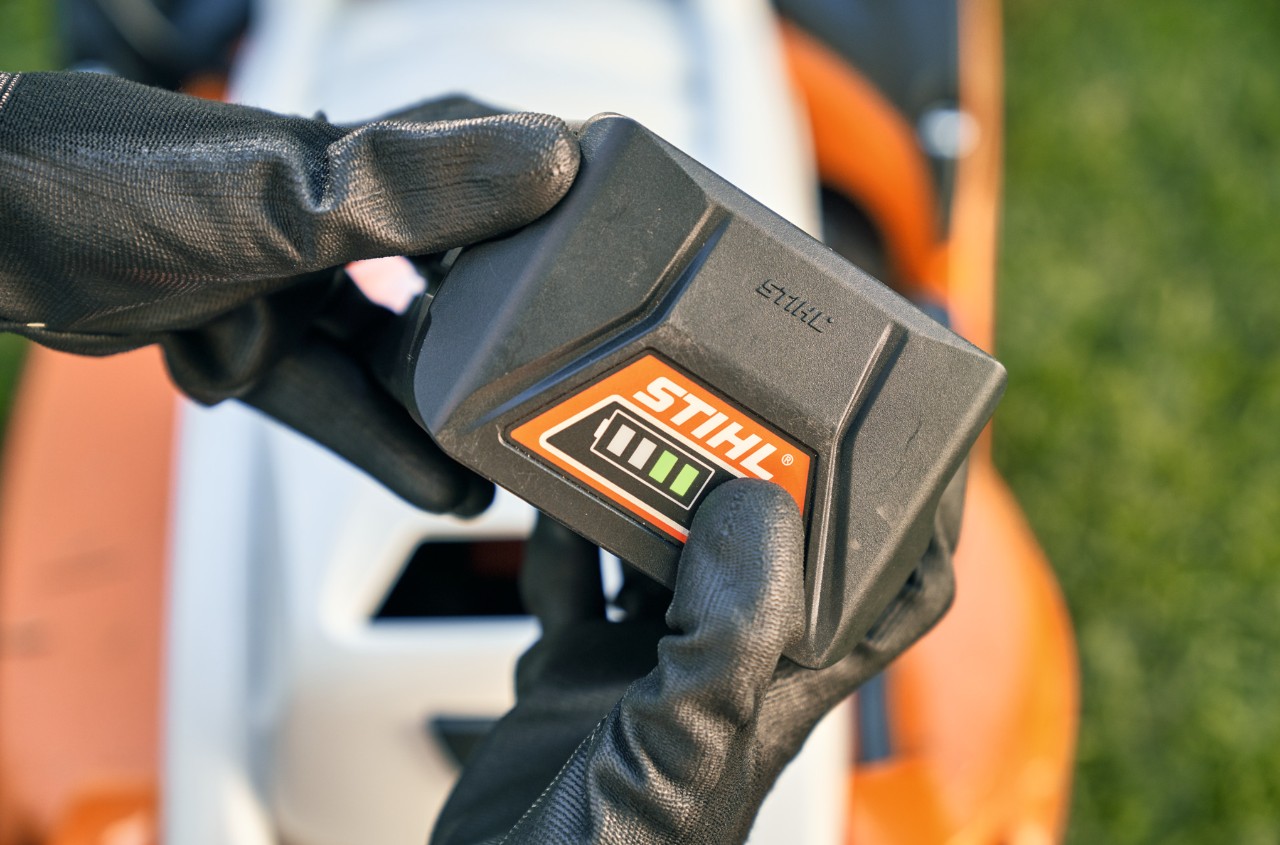 STIHL litiumionbatteri med en STIHL RMA 339 C batteridrevet gressklipper i bakgrunnen