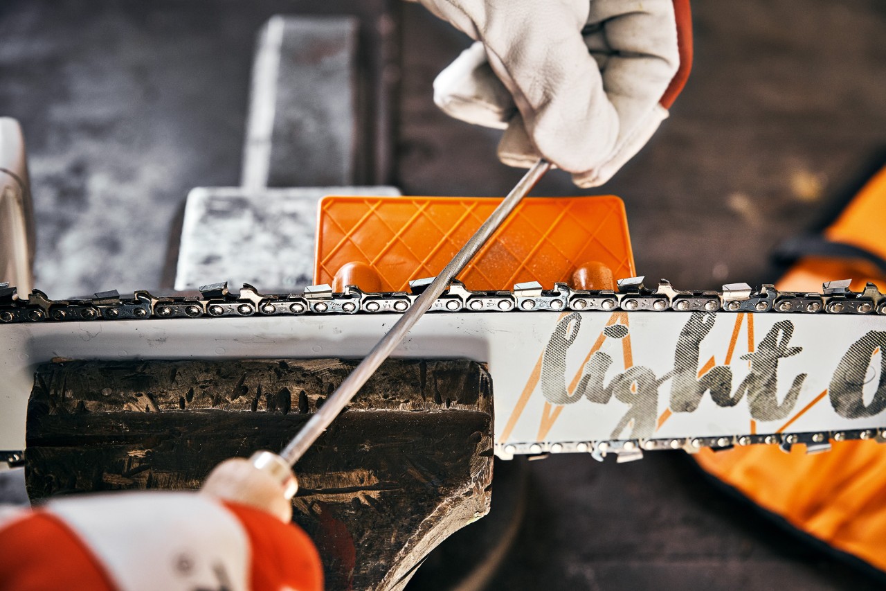 En person sliper en STIHL motorsag med en rund sagkjedefil og en STIHL filvinkelplate