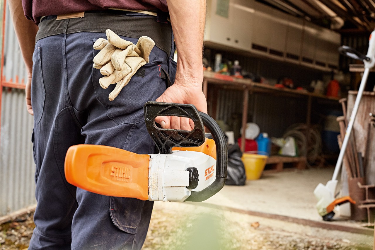 En mann som går inn på et verksted med en STIHL batteridrevet motorsag med slire