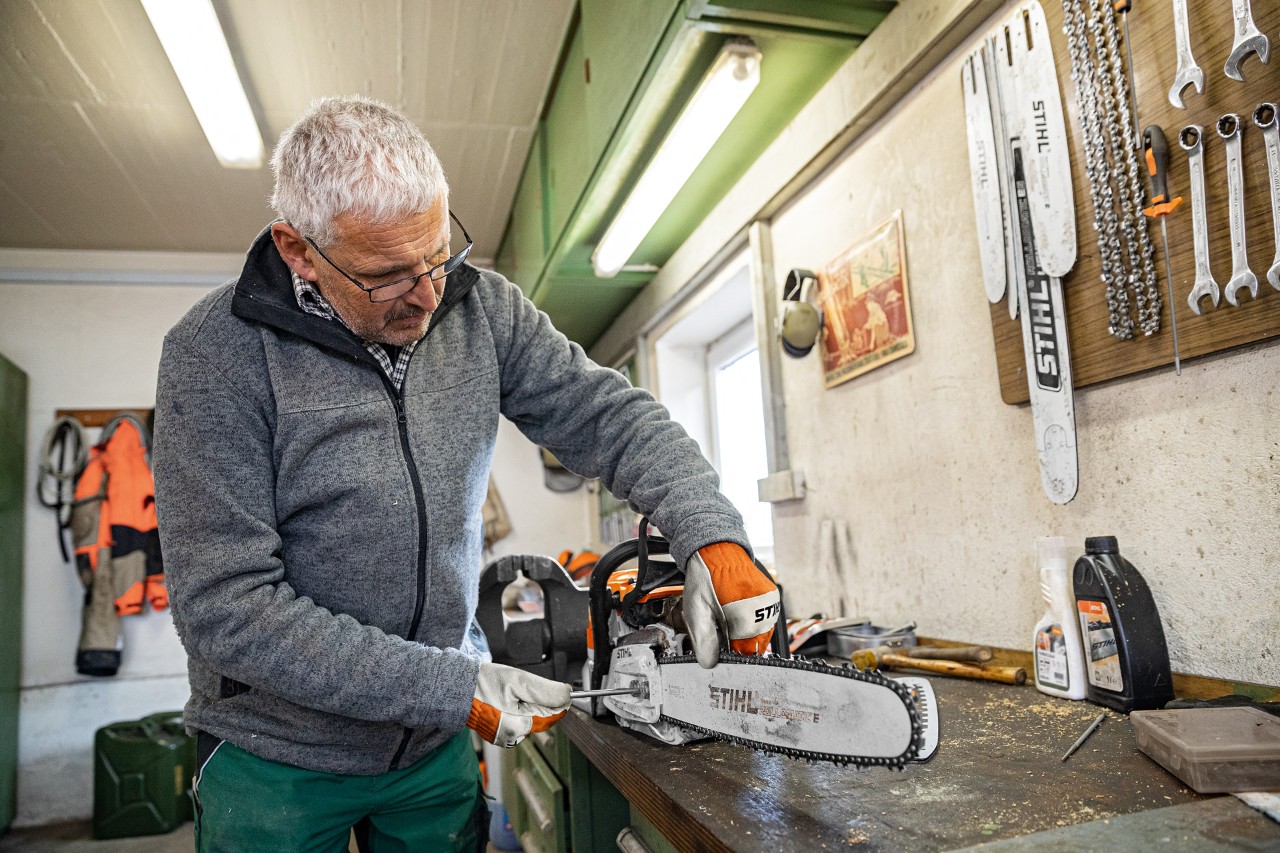 En mann strammer et STIHL motorsagkjede på et verksted