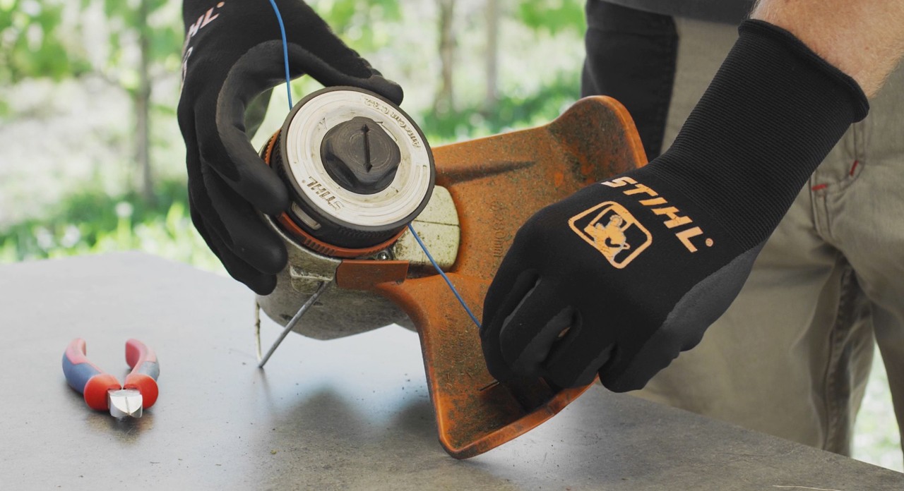 Person som vikler klippetråd inn i en STIHL FSA 57 batteridrevet ryddesag
