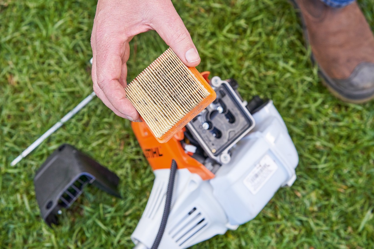 En person som tar av luftfilteret på en STIHL ryddesag for å rengjøre det 