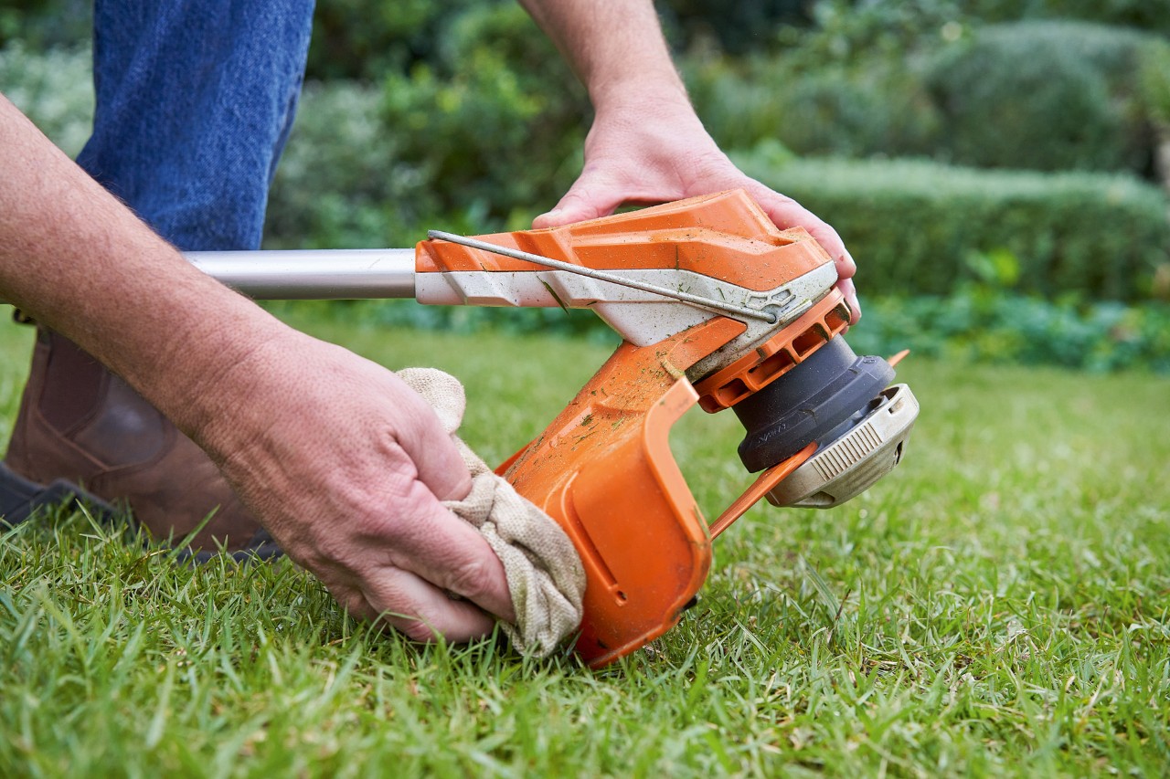 En person som rengjør dekselet på en STIHL ryddesag med en fuktig klut