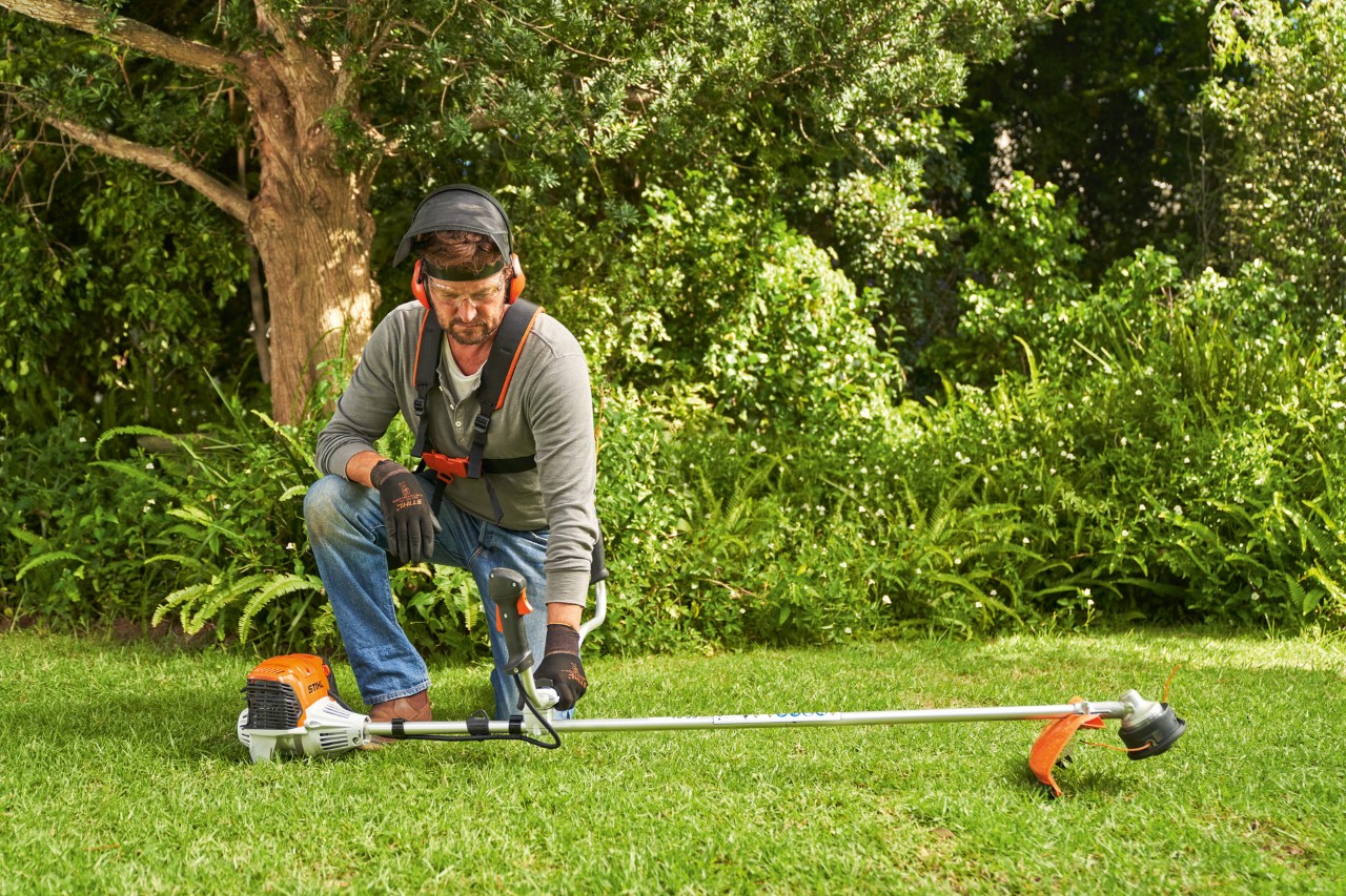 En mann som setter en STIHL FS 91 bensindrevet ryddesag på bakken før han starter den