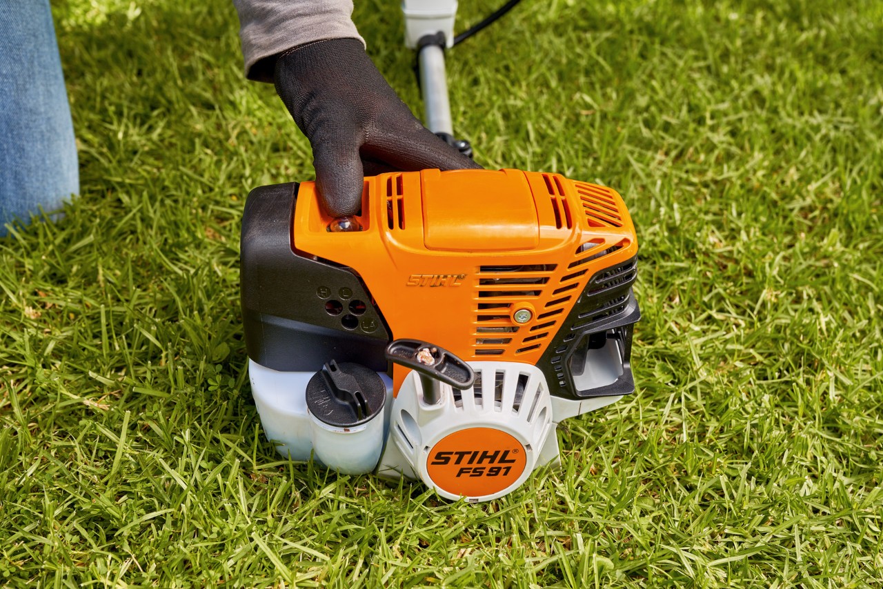En mann trykker på drivstoffpumpen til en STIHL FS 91 bensindrevet ryddesag for å starte den