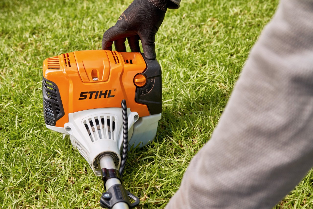 En mann trykker en STIHL FS 91 bensindrevet ryddesag godt ned på bakken