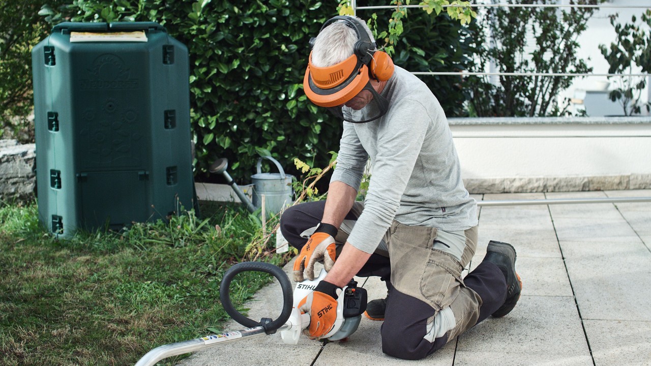 En STIHL FS 38 bensindrevet ryddesag som presses mot bakken av en person med verneklær