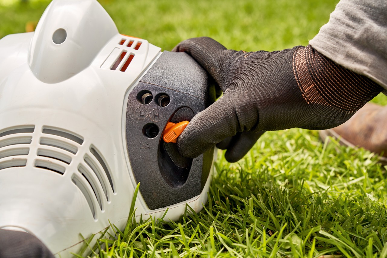 En mann justerer spaken på en STIHL FS 56 bensindrevet ryddesag for å starte den