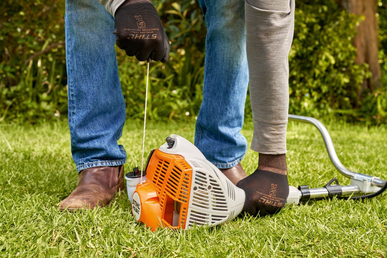 En mann som trekker i startsnoren til en STIHL FS 56 bensindrevet ryddesag 