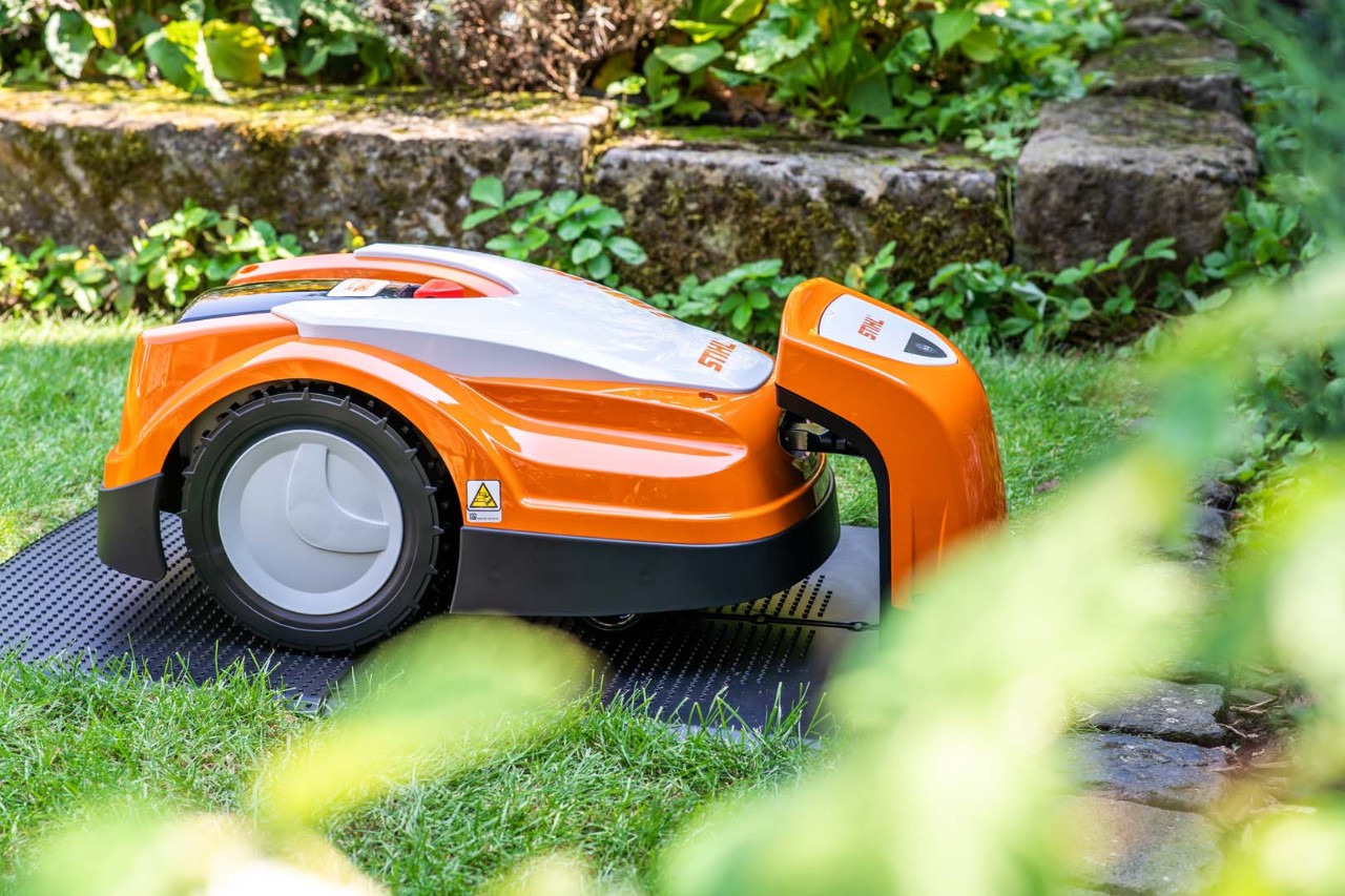 En STIHL iMOW® 422 robotgressklipper i hagen lades i ladestasjonen sin