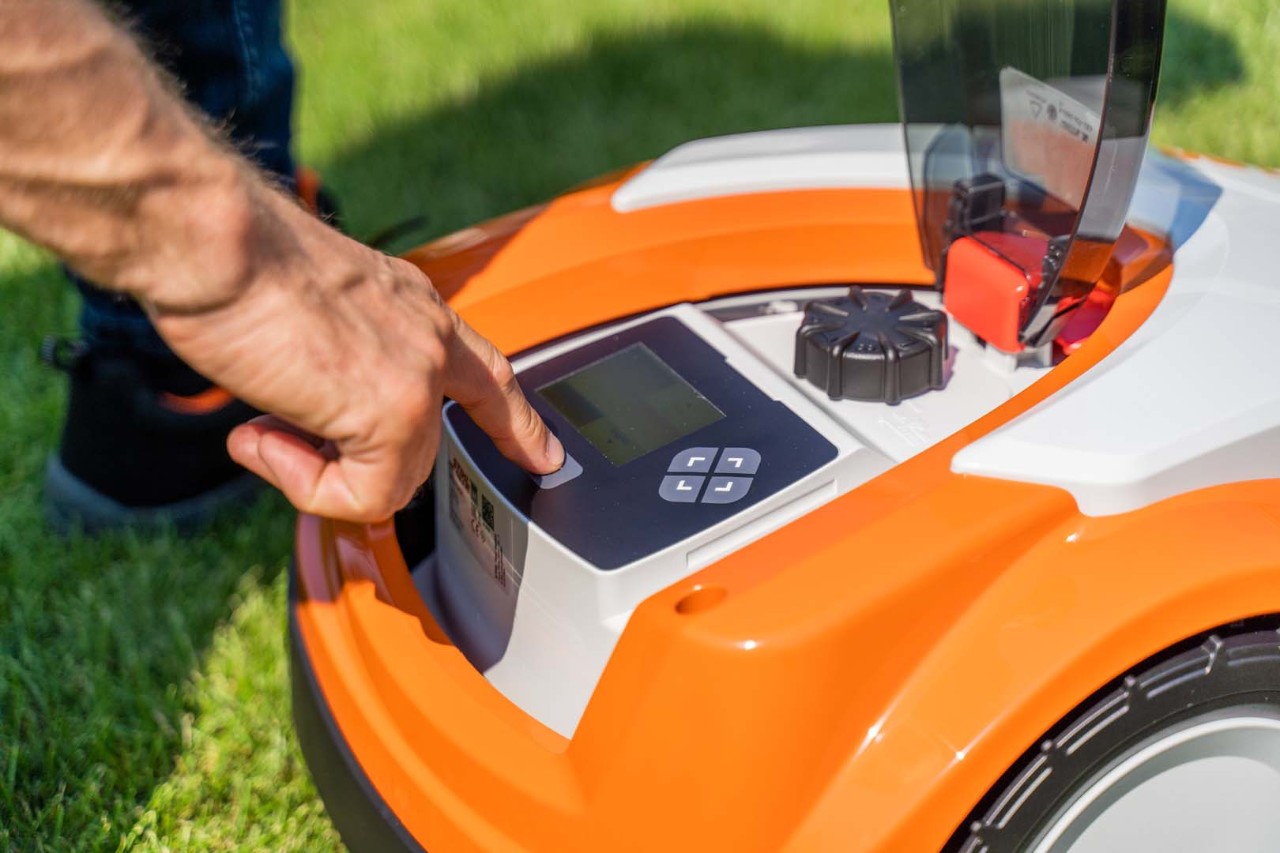 Kontrollpanelet til en STIHL iMOW® 422 robotgressklipper, og noen trykker på en knapp