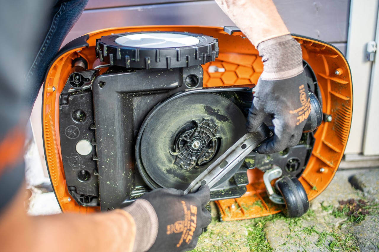 Knivbladet fjernes fra en STIHL iMOW® 422 robotgressklipper av en person med hansker