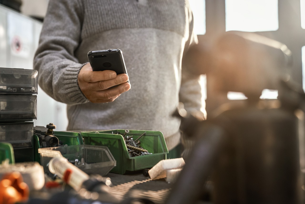 En person med smarttelefon på et verksted