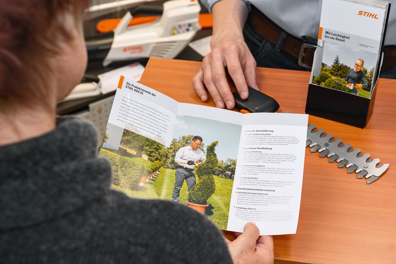 En person som leser om produktfordelene ved STIHL HSA 25 i en brosjyre