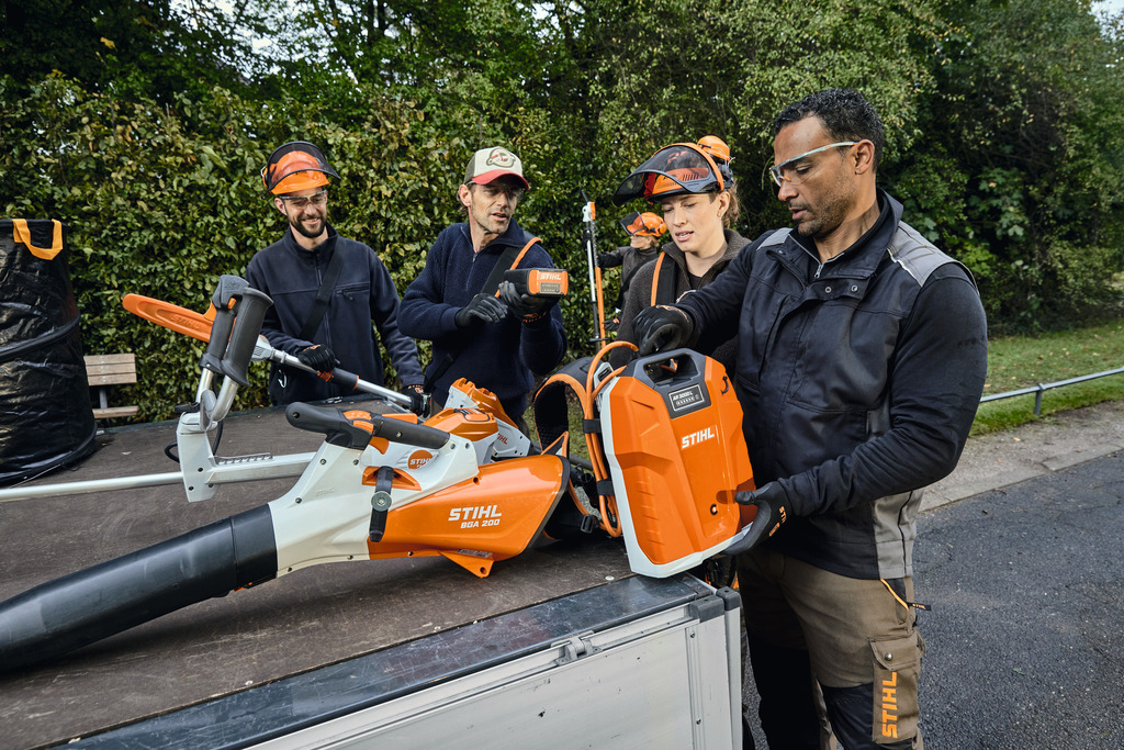 Et team av landskapsprofesjonelle laster ut sitt STIHL profesjonelle batteridrevne utstyr fra lasteområdet på et kjøretøy.