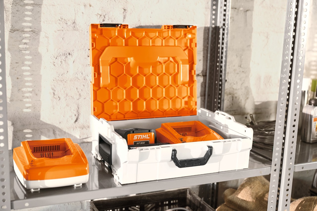 STIHL batteriboks med STIHL-batterier på en verkstedhylle  