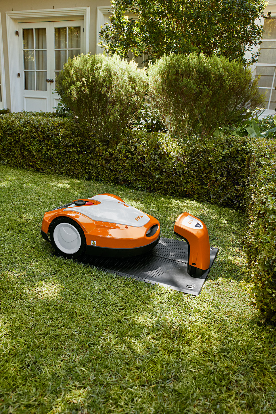 En STIHL iMOW® RMI 632 robotgressklipper i ladestasjon i en hage.