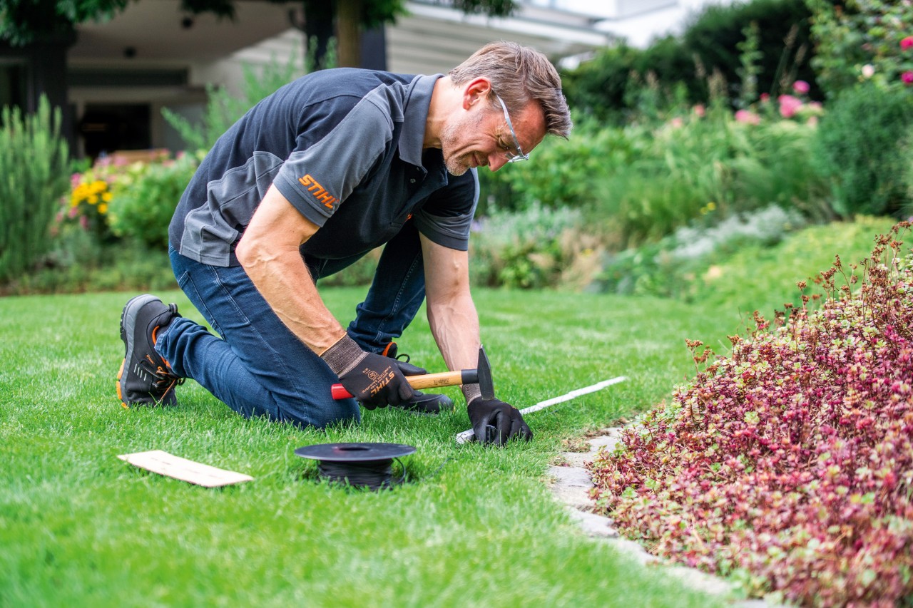 En STIHL-forhandler legger en avgrensingstråd.